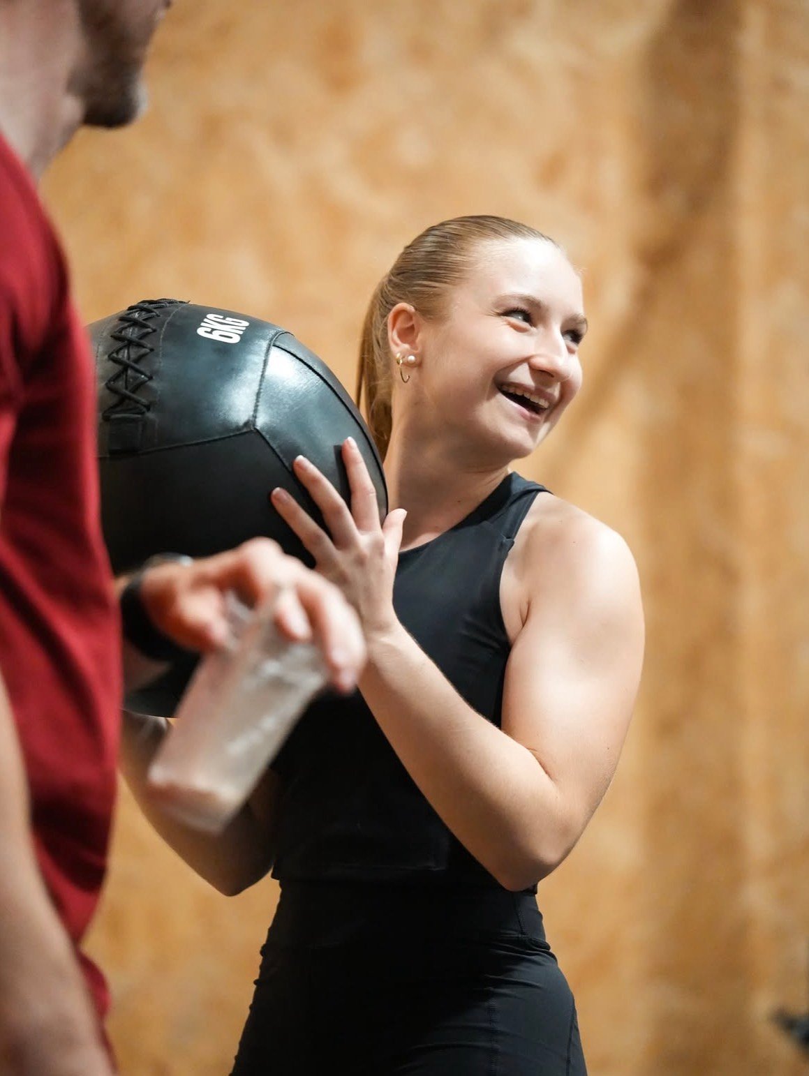 Membre souriante avec un wall ball pendant un cours de CrossFit à Albi